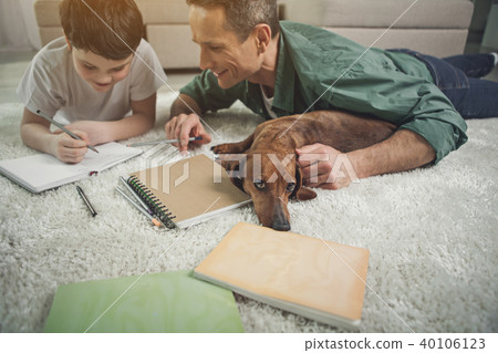 Joyful man helping child to do homework near pet Joyful man helping child to do homework near pet 40106123
