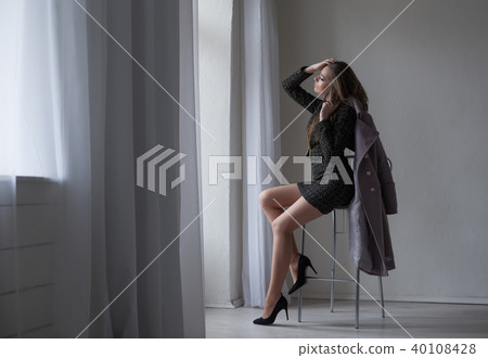 girl with gray coat sits on a Chair looking out of the window girl with gray coat sits on a Chair looking out of the window 40108428
