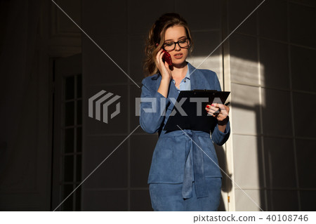 business portrait of a woman in a business suit with a Smartphone and a folder for papers business portrait of a woman in a business suit with a Smartphone and a folder for papers 40108746