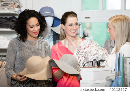 Girlfriends on shopping spree trying ladies hats 40112237