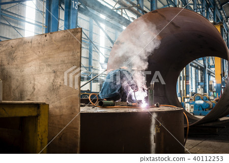 Blue-collar worker welding in the interior of a factory 40112253