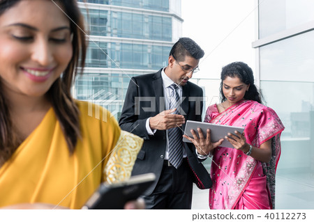 Three Indian business people using modern devices indoors 40112273