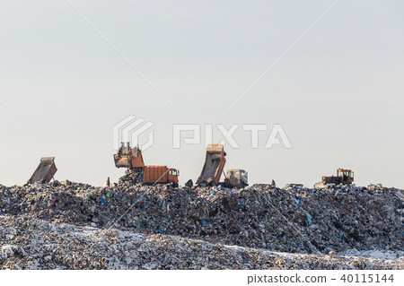 Dump trucks unloading garbage over vast landfill 40115144