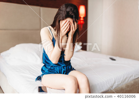 Crying woman in blue underwear sits in bed, stress 40116006