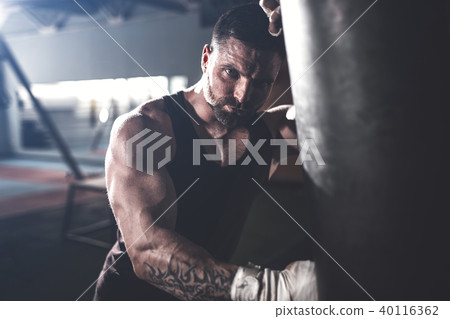 Male boxer training with punching bag in dark sports hall. Male boxer training with punching bag in dark sports hall. 40116362