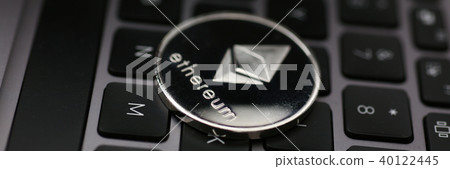 Silver ethereum coin is lying on laptop Silver ethereum coin is lying on laptop 40122445
