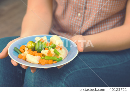 The girl holds a plate with vegetables The girl holds a plate with vegetables 40123721