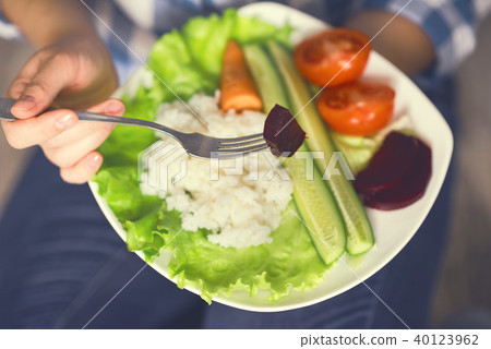 A girl holds a plate with rice and vegetables A girl holds a plate with rice and vegetables 40123962