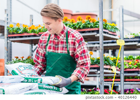 Young man carrying a bag of potting soil during work at the flower market 40126440