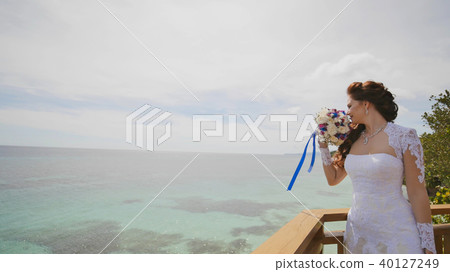 A dazzling bride enjoys happiness from the height of the balcony overlooking the ocean and reefs A dazzling bride enjoys happiness from the height of the balcony overlooking the ocean and reefs 40127249
