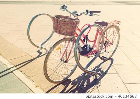 Pink vintage bicycle with basket on steering wheel 40134668