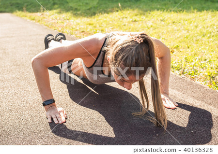 Fit woman doing push-ups at the park. 40136328