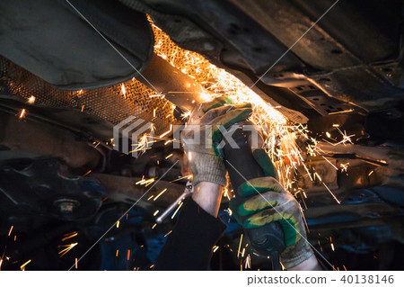 mechanic cuts old muffler on car by angle grinder 40138146