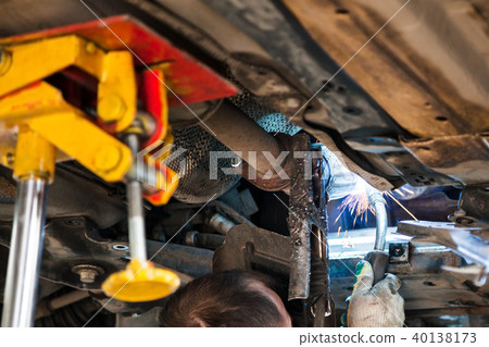 worker welds the silencer on car by argon welding worker welds the silencer on car by argon welding 40138173