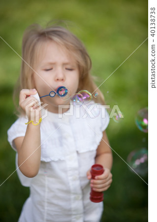 Little girl blowing soap bubbles in summer park 40138738
