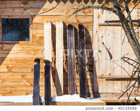 wide hunting skis in front of wooden cottage 40138998