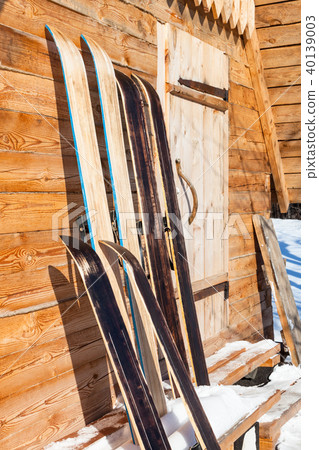 wide hunting skis near wall of wooden cottage 40139003