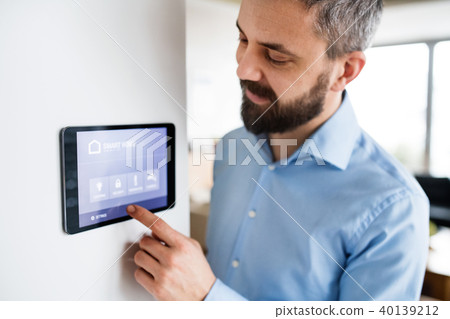 A man pointing to a tablet with smart home screen at home. A man pointing to a tablet with smart home screen at home. 40139212