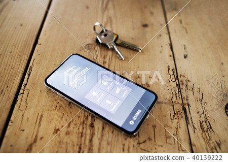 A smartphone with smart home screen and keys on wooden table. A smartphone with smart home screen and keys on wooden table. 40139222