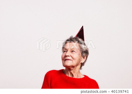 Portrait of a senior woman in studio on a gray background. Party concept. 40139741