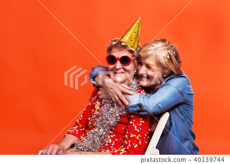 Portrait of a senior women in studio on a red background. Party concept. Portrait of a senior women in studio on a red background. Party concept. 40139744