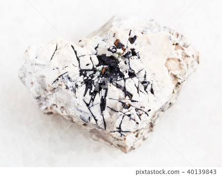 Ilmenite black crystals on raw stone on white 40139843