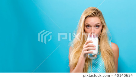 Happy young woman drinking milk on a solid background 40140654