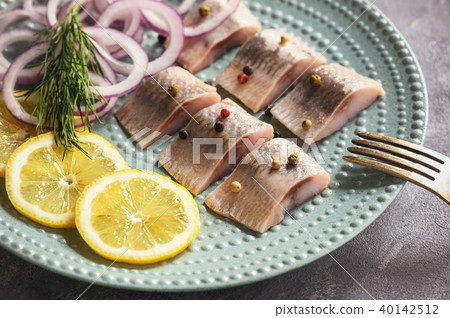 Pickled herring with red onion and lemon slices. 40142512