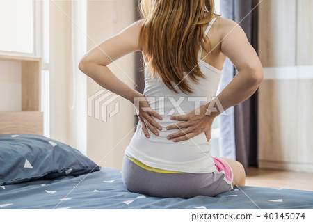 Woman suffering from back ache on the bed Woman suffering from back ache on the bed 40145074