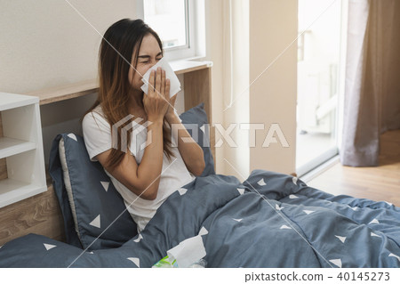 Asian woman feeling unwell and sneezing Asian woman feeling unwell and sneezing 40145273
