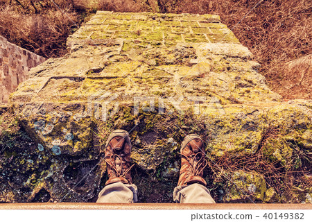 Tourist standing on high stone wall, yellow filter 40149382