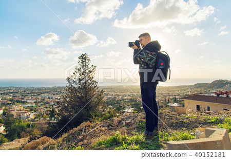 Young photographer with backpack making photos of sea and rocks with the camera. Mediterranean sea Young photographer with backpack making photos of sea and rocks with the camera. Mediterranean sea 40152181