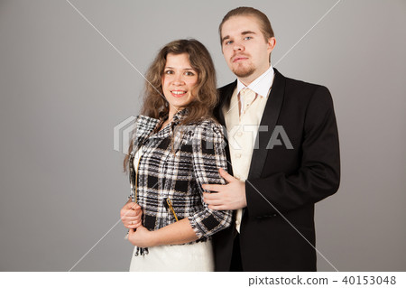 Elegant couple smiling for the camera while embracing. On grey background. Elegant couple smiling for the camera while embracing. On grey background. 40153048