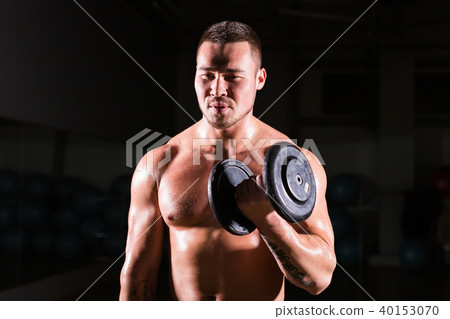 Muscular man working out in gym doing exercises with dumbbells at biceps, strong male naked torso Muscular man working out in gym doing exercises with dumbbells at biceps, strong male naked torso 40153070