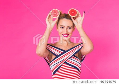 Smiling girl with grapefruit cut in half fruit in hand on pink background Smiling girl with grapefruit cut in half fruit in hand on pink background 40154079