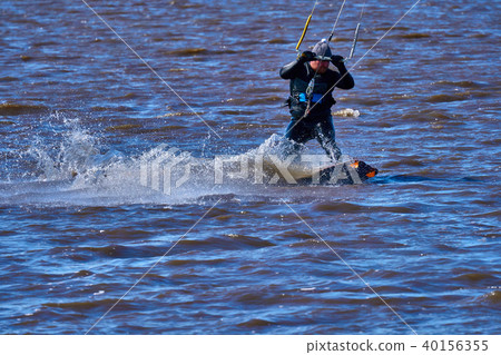 Male kiteboarder rides on a board along the river Male kiteboarder rides on a board along the river 40156355