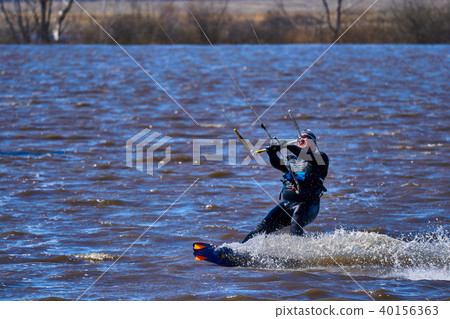 Male kiteboarder rides on a board along the river 40156363