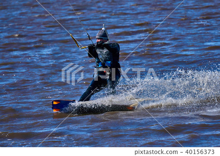 Male kiteboarder rides on a board along the river Male kiteboarder rides on a board along the river 40156373