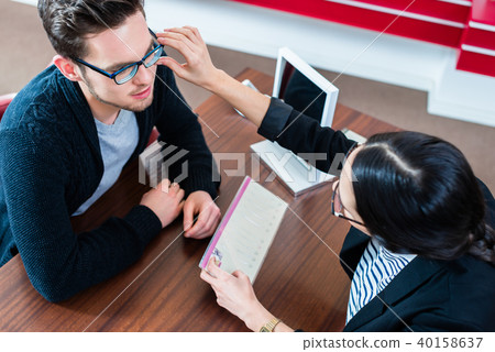 Customer and sales woman in optician store 40158637