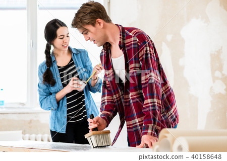 Young couple sharing tools while working on improvement of their house Young couple sharing tools while working on improvement of their house 40158648