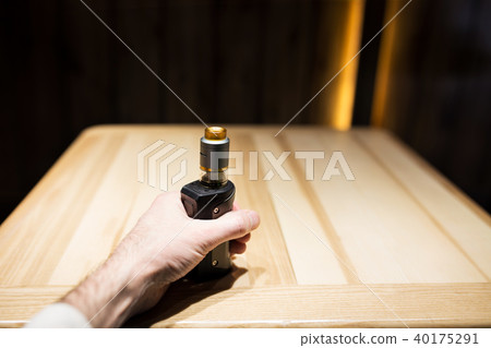 A man's hand holds vape in a cafe, safe smoking A man's hand holds vape in a cafe, safe smoking 40175291