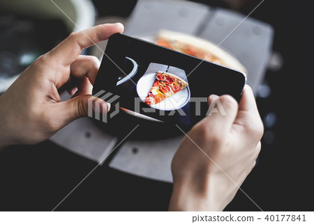 A young man taking photo of pizza on smartphone, photographing meal with mobile camera. Top view A young man taking photo of pizza on smartphone, photographing meal with mobile camera. Top view 40177841