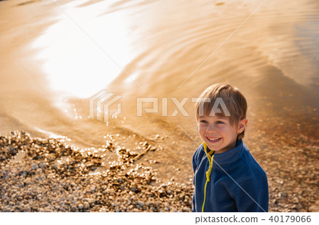 blond child smiles by the lake at sunset 40179066