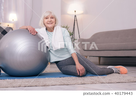 Cheerful elderly lady posing while leaning on yoga ball 40179443