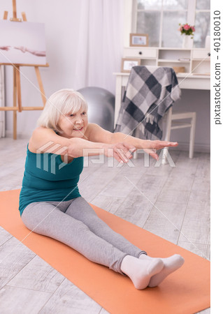 Elderly lady stretching while warming up before workout 40180010