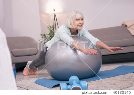 Pleasant elderly woman lying on exercise ball 40180140
