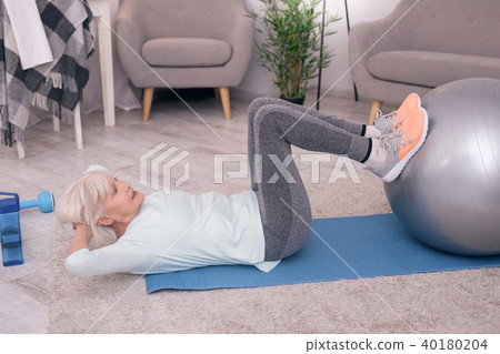 Pleasant elderly woman doing sit-ups 40180204