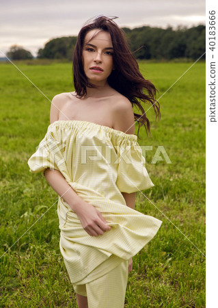 woman in yellow dress stands in a field woman in yellow dress stands in a field 40183666
