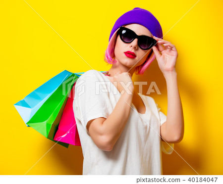 Young girl with shopping bags on yellow background 40184047