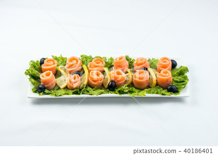salmon snack on lettuce leaf with lemon and olives on white plate on white background 40186401